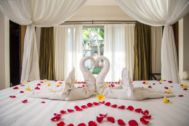 Luxury hotel bedroom interior with honeymoon decoration, Towel swans and rose flowers on the bed